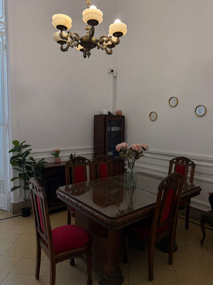 Comedor luminoso con mesa de madera tallada y araña de bronce