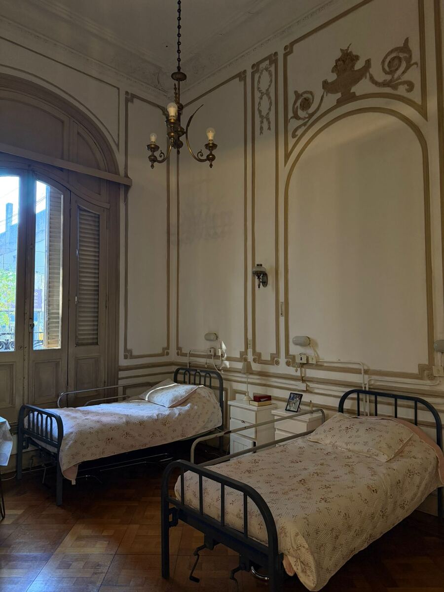 Habitación de techo alto con dos camas y puerta ventana al balcón